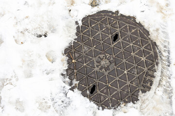 zasypana śniegiem studzienka kanalizacyjna.