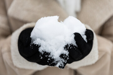 kobieta trzyma w rękach świeży śnieg. Zbliżenie na ręce