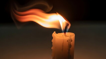 Dramatic candle flame burning brightly in darkness