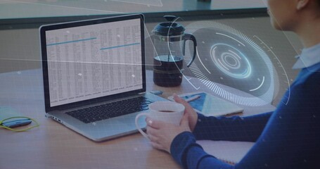 Holding mug, woman in blue sweater analyzing spreadsheet on laptop at desk with HUD, copy space