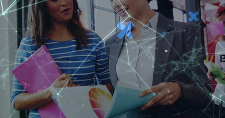 Reviewing duo reading color wheel brochure and pink folder in office with network overlay in blazer