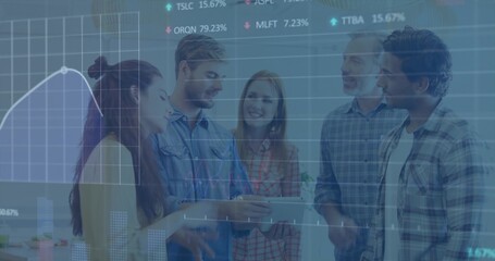 Reviewing group of five in casual shirts, leaning around tablet in office, showing finance charts