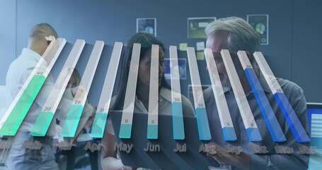 Examining midlife woman and man in suits reviewing tablet at office, 3D bar chart, monitors