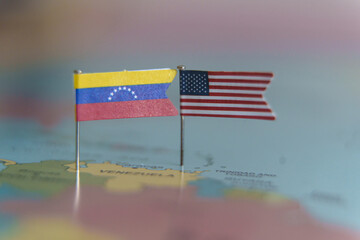 Close up of small Venezuela and United States flags pinned on a world map over South America.
