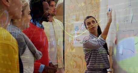 Writing presenter in striped top sketching on board with marker in meeting room, charts, copy space