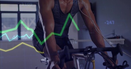 Pedaling cyclist in gray top, black shorts on exercise bike in gym with earphones, metrics overlays