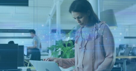 Standing woman in pink blouse typing on laptop at open office with plant and blue overlay