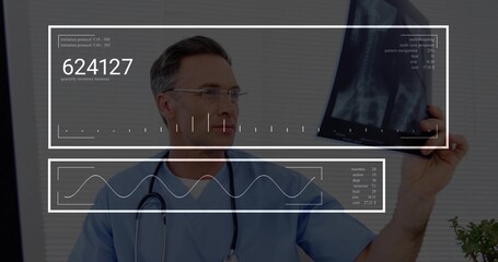 Mature male doctor examining radiograph in clinic, wearing blue scrubs and viewing HUD overlays