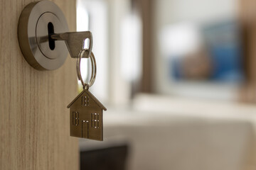 Open door to a new home. Door handle with key and home shaped keychain. Mortgage, investment, real estate, property and new home concept