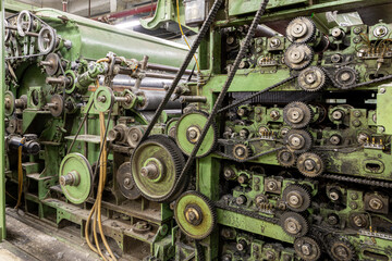 Complex vintage industrial machine with gears, chains, and belts. Closeup of old green factory equipment from the industrial revolution era