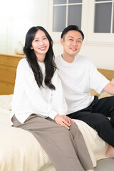 夜の寝室で笑顔で会話をする日本人男女