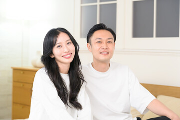 夜の寝室で笑顔で会話をする日本人男女