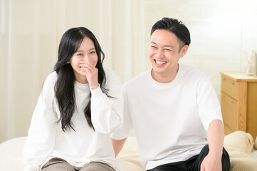 夜の寝室で笑顔で会話をする日本人男女