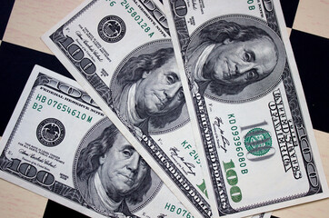 One hundred American dollars close-up on a chessboard background. National currency of the United States of America