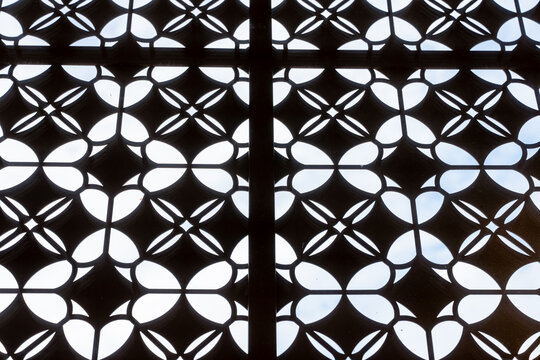 Mur m&eacute;tallique perfor&eacute; pr&eacute;sentant un motif floral g&eacute;om&eacute;trique r&eacute;p&eacute;titif, illustrant un design architectural moderne et d&eacute;coratif.