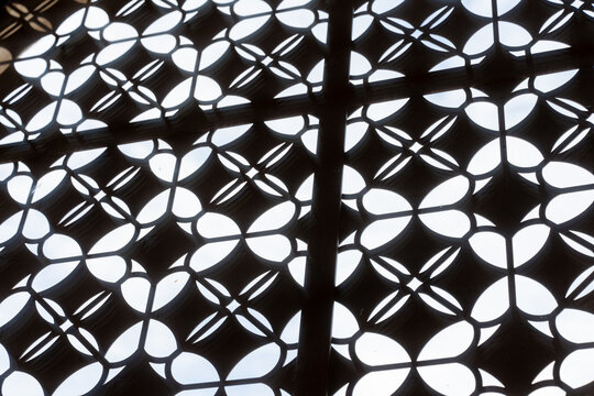 Mur m&eacute;tallique perfor&eacute; pr&eacute;sentant un motif floral g&eacute;om&eacute;trique r&eacute;p&eacute;titif, illustrant un design architectural moderne et d&eacute;coratif.