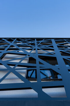 Vue d&rsquo;une devanture de b&acirc;timent avec des &eacute;l&eacute;ments en m&eacute;tal bleu, mettant en valeur une fa&ccedil;ade architecturale moderne aux lignes industrielles et aux couleurs contrast&eacute;es.