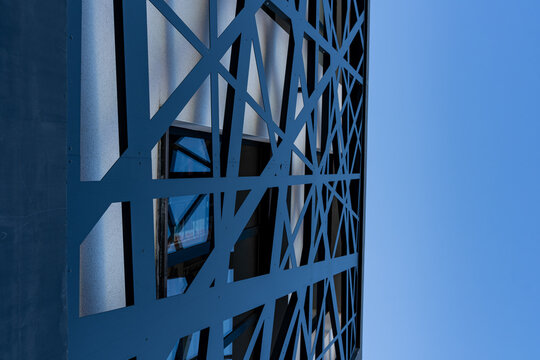 Vue d&rsquo;une devanture de b&acirc;timent avec des &eacute;l&eacute;ments en m&eacute;tal bleu, mettant en valeur une fa&ccedil;ade architecturale moderne aux lignes industrielles et aux couleurs contrast&eacute;es.