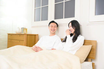 夜の寝室で笑顔で会話をする日本人男女