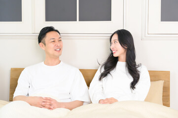 夜の寝室で笑顔で会話をする日本人男女