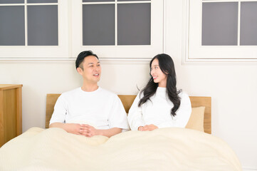 夜の寝室で笑顔で会話をする日本人男女