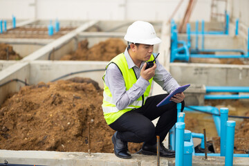 walkie talkie, Asian Man working, Architect or contractor working on house building under construction. Professional Architects Engineer construction site. Civil Engineering in safety harthat helmet