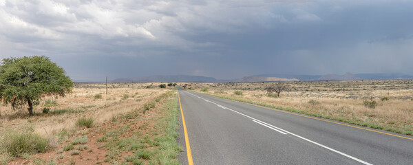 storm clouds over C23 road in green country landscape near Elizenhohe, Namibia