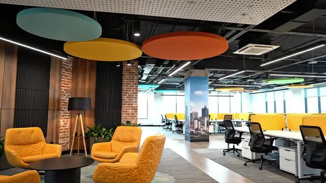 Modern office space with yellow chairs and colorful ceiling decorations, featuring a collaborative workspace and comfortable seating areas.