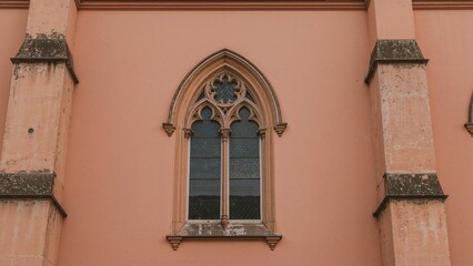 Fototapeta premium A church window on a pink building with gothic architecture details.