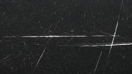 A close up view of a heavily scratched and damaged black surface texture