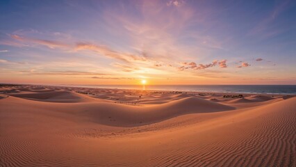 Sunset over the desert with sand dunes and a colorful sky.