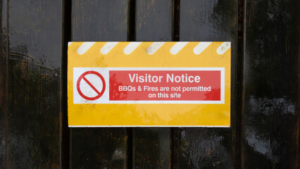 Visitor Notice - No BBQs or Fires sign - on wooden door background