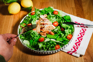 woman eating chicken salad with green lettuce, grilled chicken meat, green peas, lemons, fresh natural healthy mediterranean meal