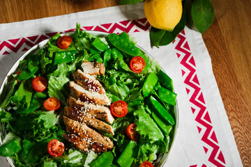 healthy chicken salad with lettuce, green peas, cherry tomatoes, olive oil dressing, close up