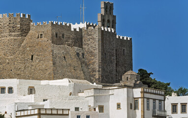 Monastery of Saint John the Theologian in Patmos, Greece, composed of large stone blocks with crenellated battlements and towers overlooking a cluster of white buildings with flat roofs 