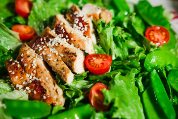 healthy chicken salad with lettuce, green peas, cherry tomatoes, olive oil dressing, close up