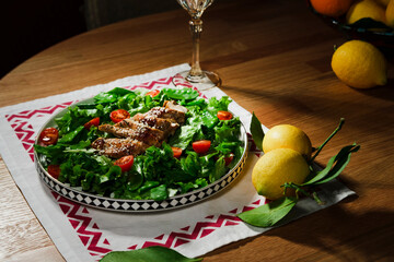 mediterranean styled salad with green lettuce leaves, peas, grilled chicken meat, cherry tomatoes, dressed with olive oil, served for one