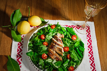mediterranean styled salad with green lettuce leaves, peas, grilled chicken meat, cherry tomatoes, dressed with olive oil, served for one