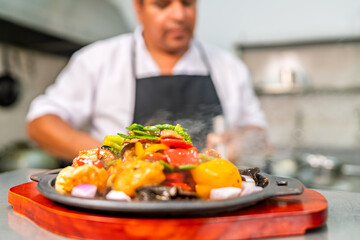 Chef finishing hot chinese peruvian fusion dish in kitchen