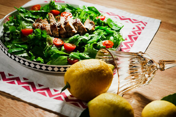 mediterranean styled salad with green lettuce leaves, peas, grilled chicken meat, cherry tomatoes, dressed with olive oil, served for one
