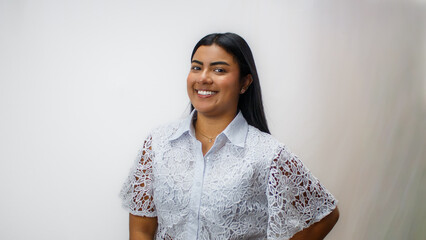Retrato profesional de mujer joven con gafas, sonriente, vestida con blusa blanca de encaje, estilo corporativo femenino, fondo claro, concepto de confianza, atención al cliente y éxito profesional © Les Taylor