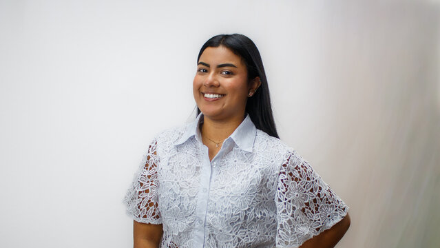 Retrato profesional de mujer joven con gafas, sonriente, vestida con blusa blanca de encaje, estilo corporativo femenino, fondo claro, concepto de confianza, atenci&oacute;n al cliente y &eacute;xito profesional