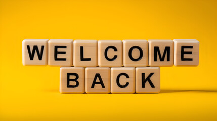Wooden blocks spelling welcome back greeting on yellow background