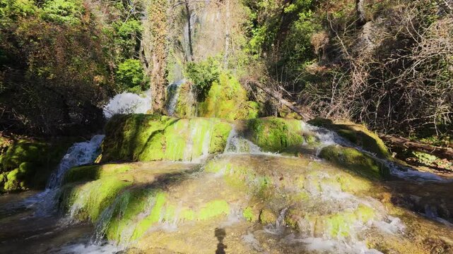 Serene winter landscape at the Fuentetoba waterfall, where the Golmayo River gently cascades over vibrant green mossy rocks in a beautiful natural park located in the province of Soria, Spain.
