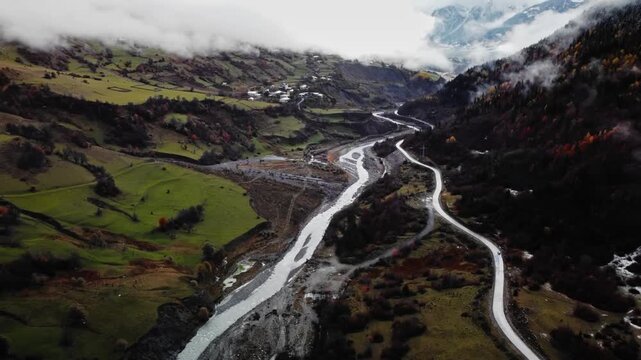 braided river carving through autumn valley with winding roads and meandering channels, aerial view reveals dynamic lines and earthy tones, composition emphasizes movement, natural engineering