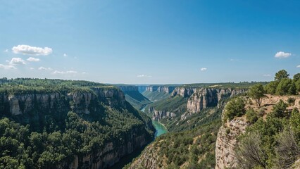 Aerial view of a canyon with cliffs, lush greenery, and a river flowing through, under a blue sky with scattered clouds.