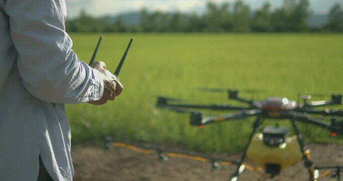Smart farmer using drone controller or drone transmitter a remote control for agriculture sprayer drone in rice paddy field in rural area countryside farm landscape