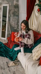 Young woman enjoying a festive hot chocolate with marshmallows on a cozy couch