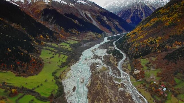 Aerial braided river slicing through valley with farm plots and scattered village, pastoral textures, grazing land and mountain backdrop emphasize rural culture and sustainable agriculture narratives