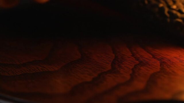 Close-up of a dark wooden surface, showcasing the elegant, wavy grain and rich, natural texture. This abstract pattern highlights organic design and rustic warmth in timber